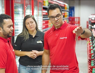 Equipo de gestión comercial asesorando en el pasillo de un supermercado, reflejando el compromiso de la compañía con el crecimiento de sus clientes minoristas.
