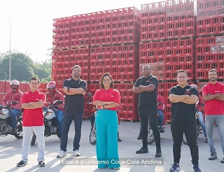 Grupo diverso de colaboradores de KoAndina posando con confianza frente a racks de carga roja, destacando el capital humano como motor del propósito corporativo.
